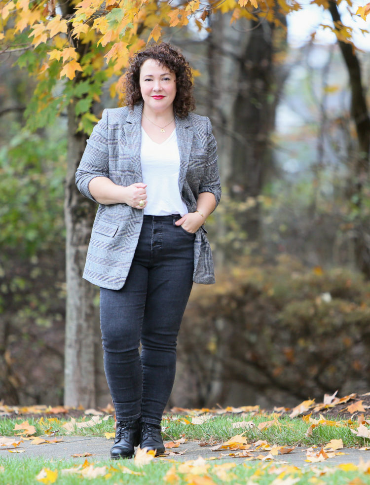 Alison of Wardrobe Oxygen looking at the camera, one hand holding the lapel of an Everlane Oversized Blazer in gray plaid, the other tucked in the pocket of dark gray button-fly skinny jeans.