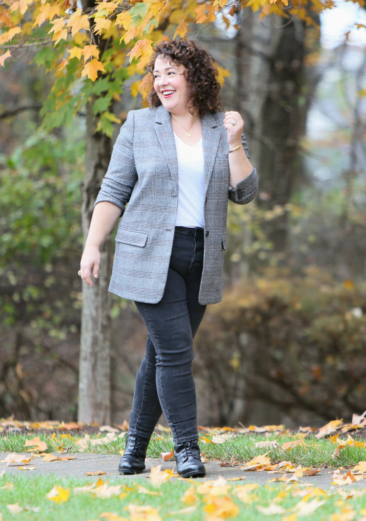 Alison of Wardrobe Oxygen wearing the Everlane Oversized Blazer in gray plaid with a white v-neck t-shirt and skinny gray trousers. She is smiling and looking away from the camera.