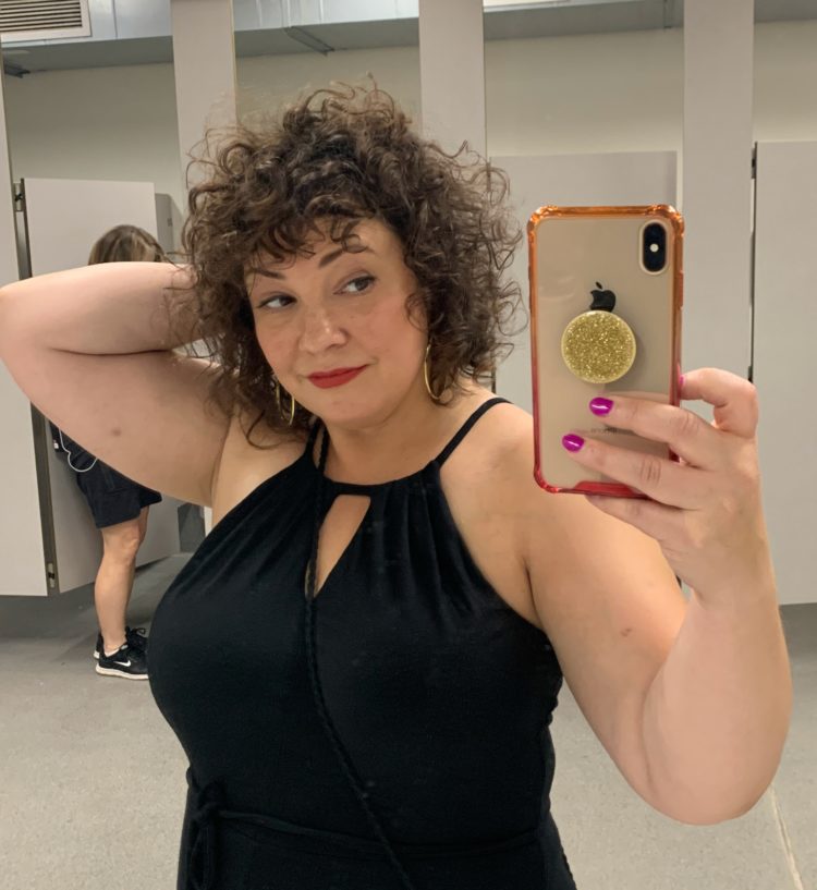 woman taking a mirror selfie with full curly brown hair