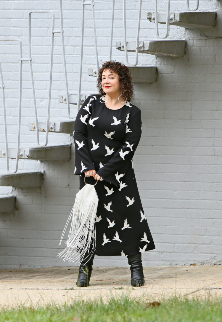 Black Stine Goya dress with white bird print styled with Kara Bags fringed purse and black heeled knee high boots