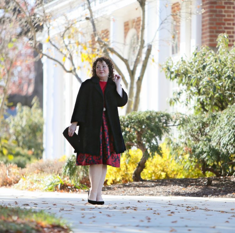 Black vintage coat with a red cashmere sweater tucked into the Talbots red floral jacquard skirt