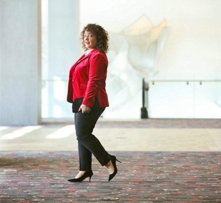 Alison in a red blazer walking away from the camera