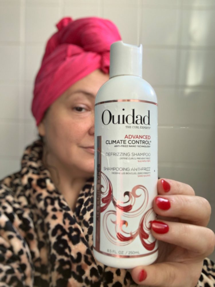 holding a bottle of ouidad climate control shampoo