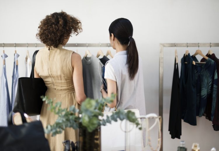 two women perusing a clothing rack in a store