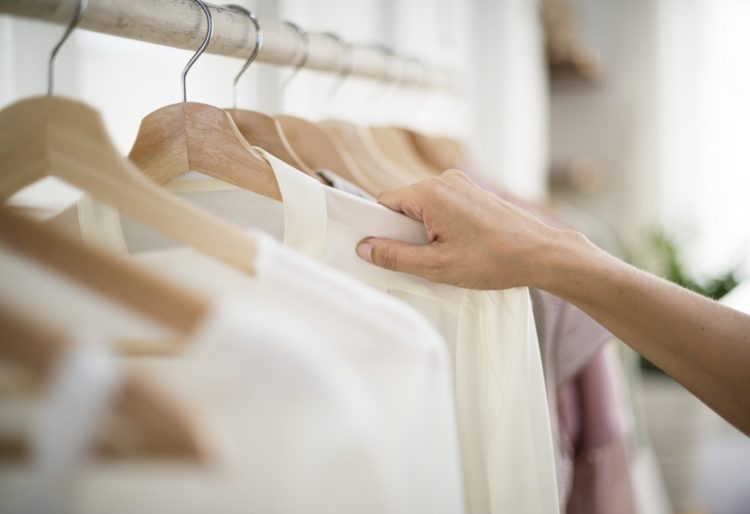 woman's hand selecting a blouse from a clothing rack