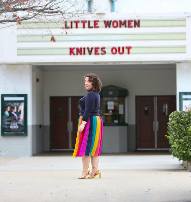 Woman wearing a rainbow stripe chiffon midi skirt and looking at the camera