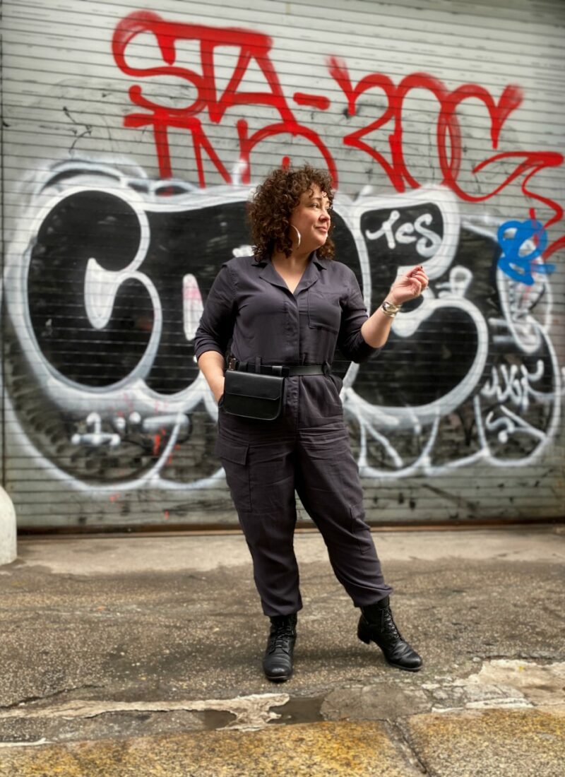 Alison of Wardrobe Oxygen in a gray boilersuit with a black leather belt bag and silver hoops from Jenny Bird