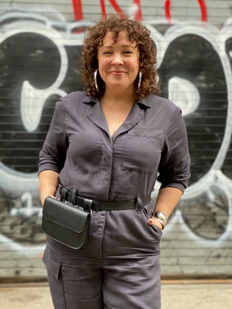 Alison of Wardrobe Oxygen in a gray boilersuit with a black leather belt bag and silver hoops from Jenny Bird