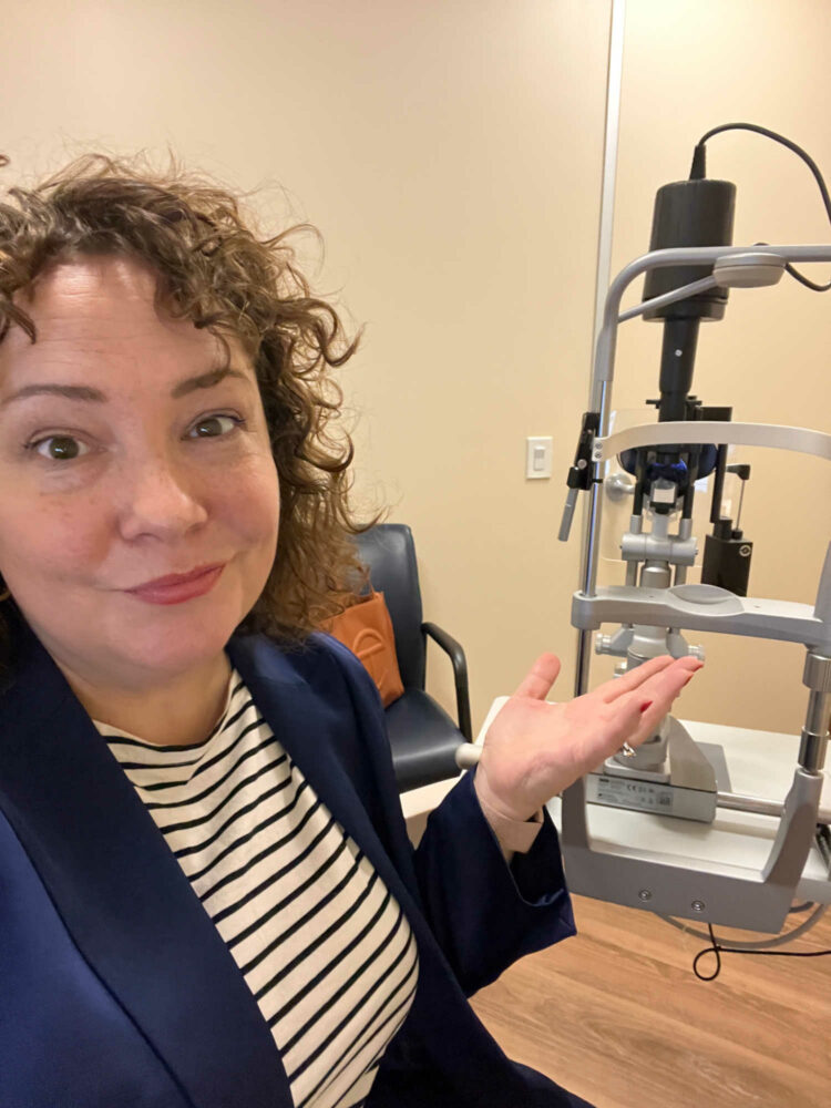 woman sitting in an exam chair at a retina specialist's office with the laser and magnifying tool behind her.x