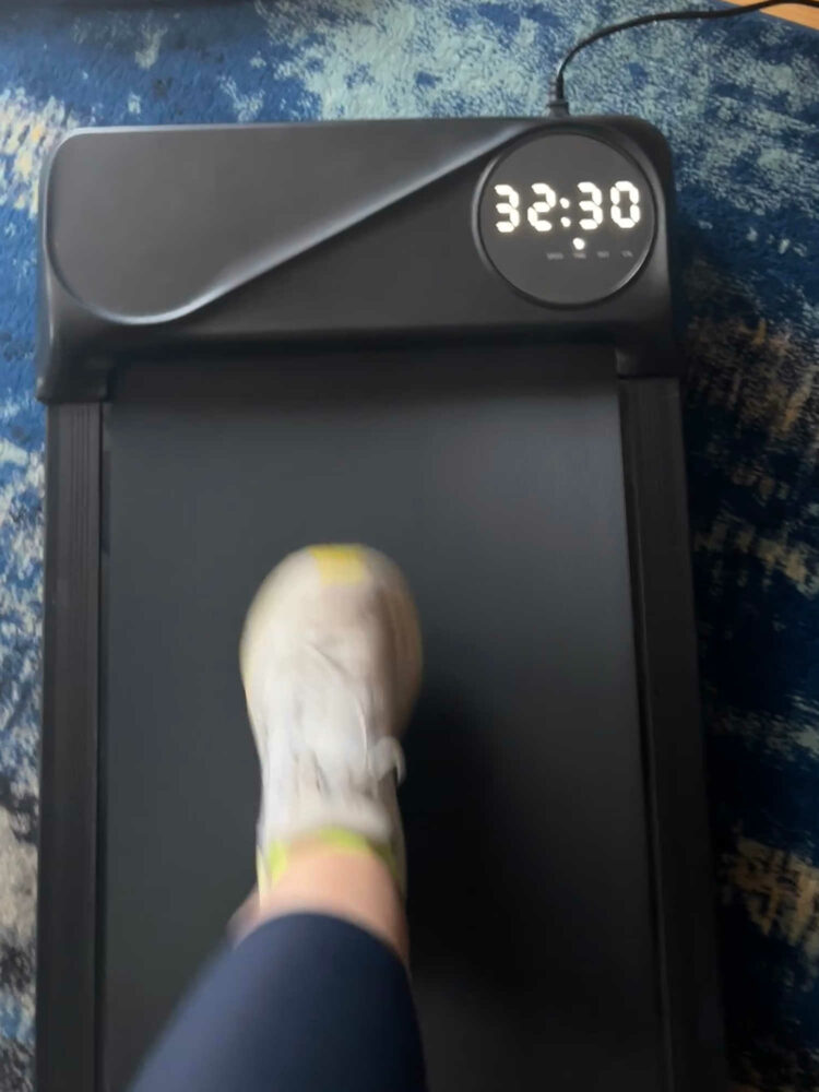 a woman's foot wearing a sneaker moving on a walking pad. It shows that she has already gone 32.5 minutes on the mini treadmill