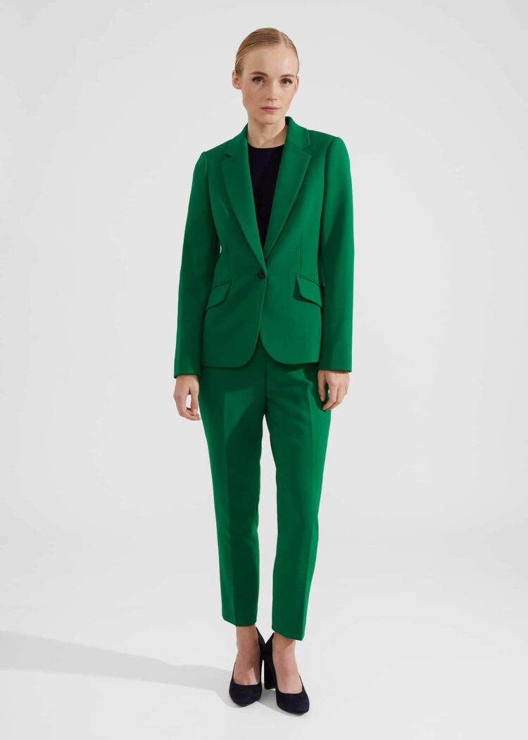 a petite blonde model on the Hobbs London website wearing a bright green single breasted blazer and matching ankle pants with a black crewneck blouse and black low-heeled pumps.