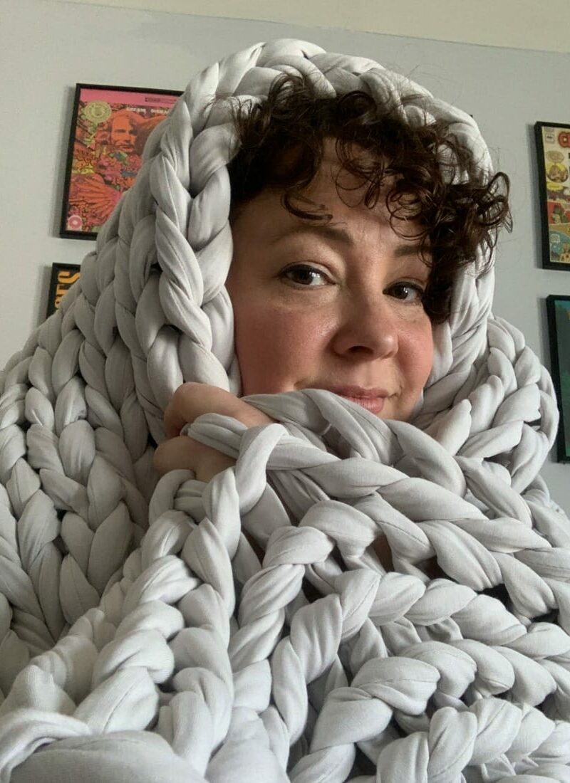 alison wrapped up in a pale gray wide knit blanket called the tree napper