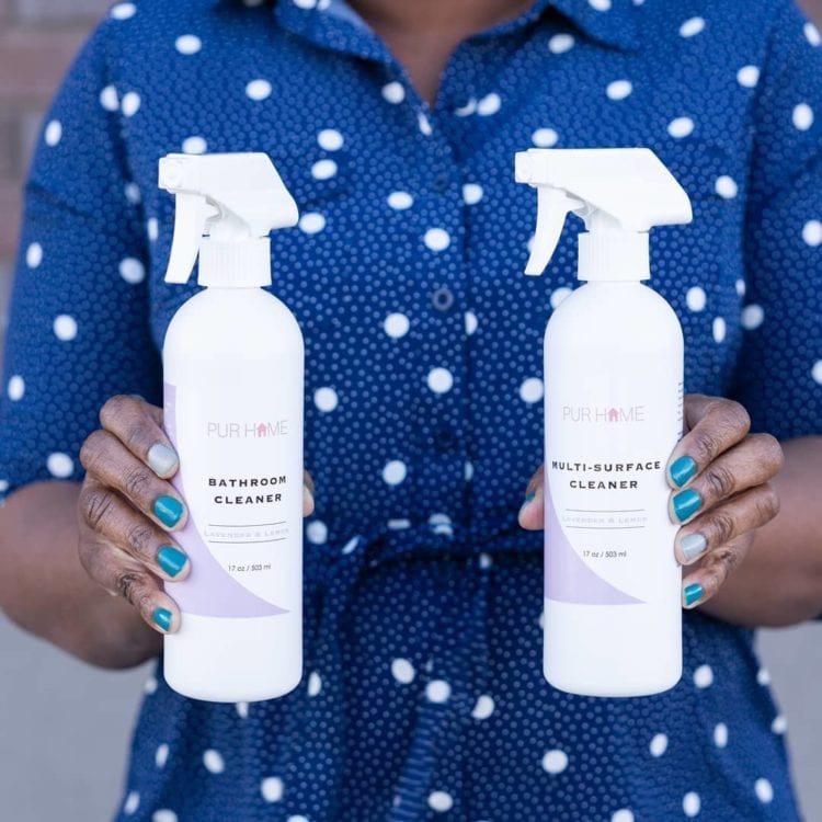 Woman holding bottles of cleaning products from PUR HOME