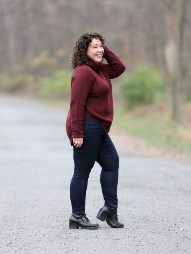 Woman in a burgundy turtleneck sweater and Universal Standard Seine skinny jeans