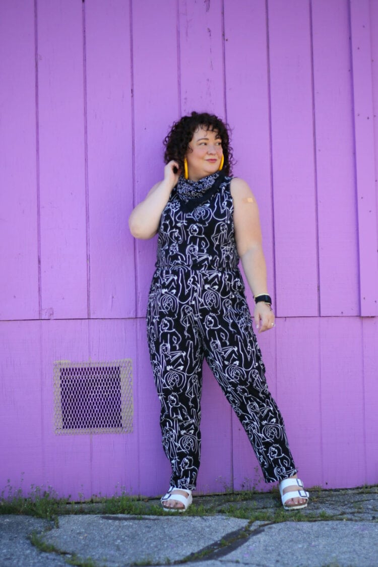 Woman in a black and white knit Dazey LA top and pants and wearing big yellow hoop earrings standing in front of a purple wall