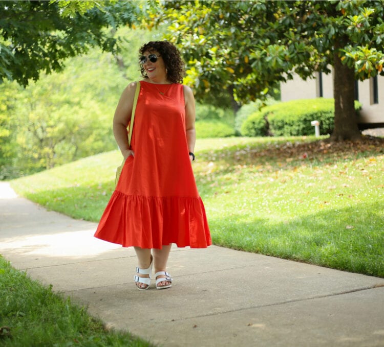 Alison in the Christopher John Rogers for Target Orange Shift Dress wearing aviator sunglasses as she walks down a sidewalk