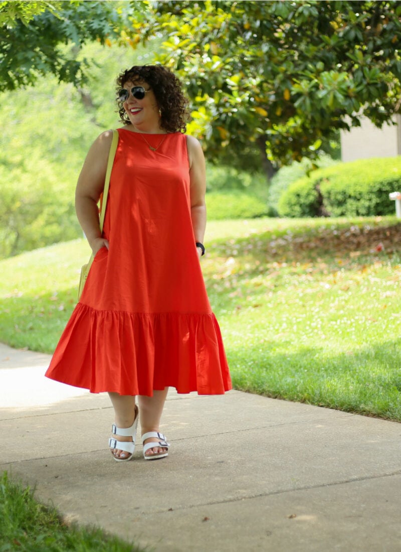 Alison in the Christopher John Rogers for Target Orange Shift Dress wearing aviator sunglasses as she walks down a sidewalk