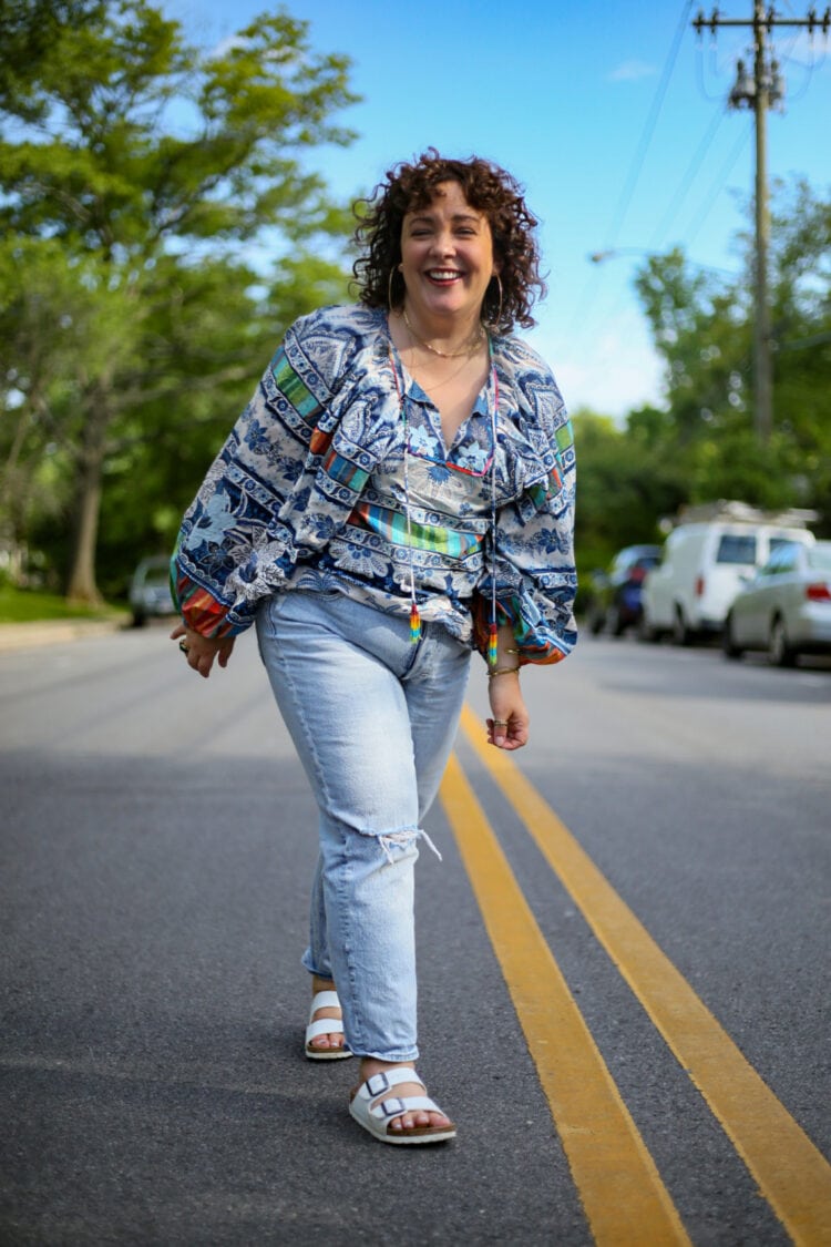 Alison walking towards the camera laughing while wearing a blue and white print Farm Rio top and faded distressed Gap jeans