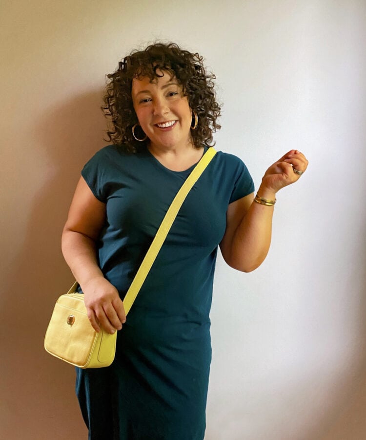 Alison in a teal knit t-shirt dress with a yellow crossbody bag