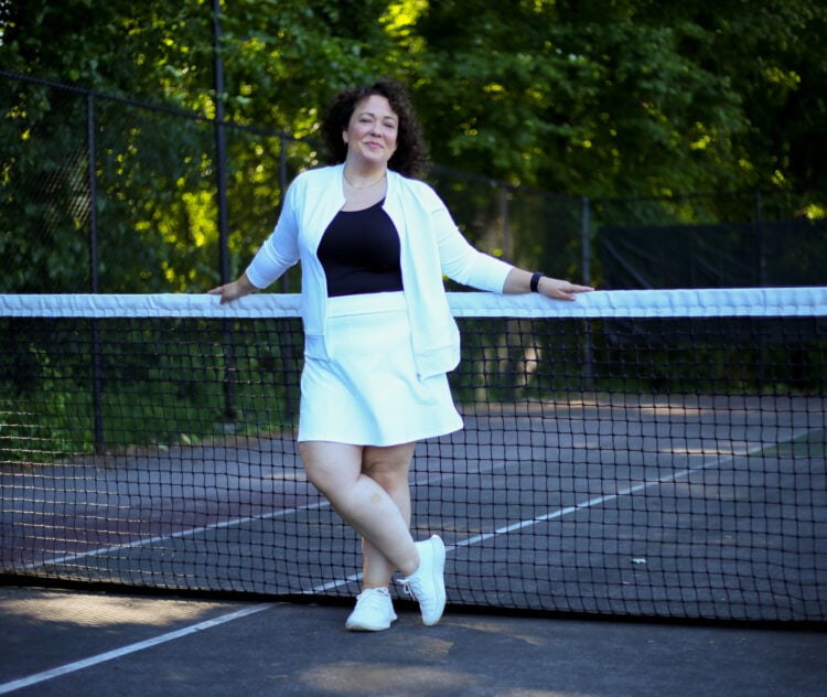 Alison of Wardrobe Oxygen in a white bomber jacket and skort with a black tank and white Allbirds sneakers