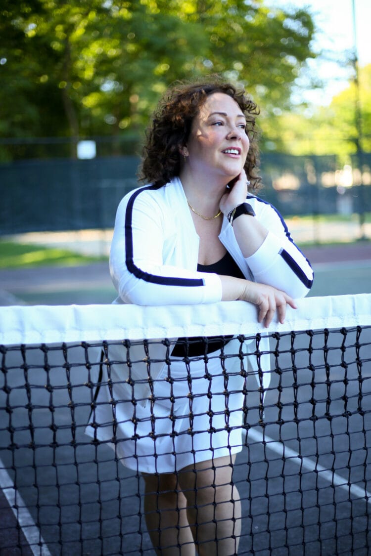 Alison in a white bomber jacket with a black stripe down the arm and a matching skort. Both are from Talbots.