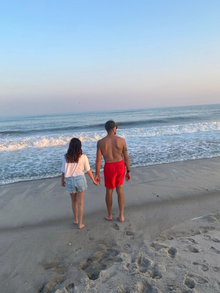 Fire Island Capsule Wardrobe: What I Packed for a Week in August 1 A man and his tween daughter holding hands, standing on a beach, looking at the sunset