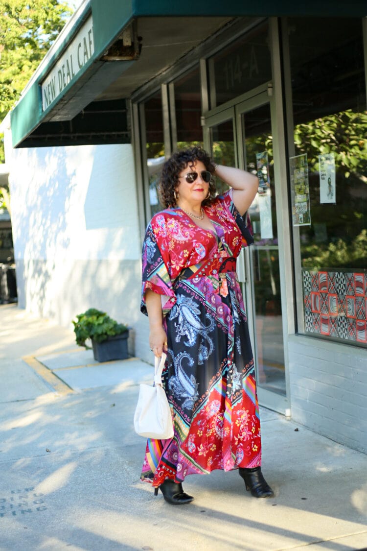 Wardrobe Oxygen standing outside the New Deal Cafe wearing a red printed maxi dress carrying an ivory bag