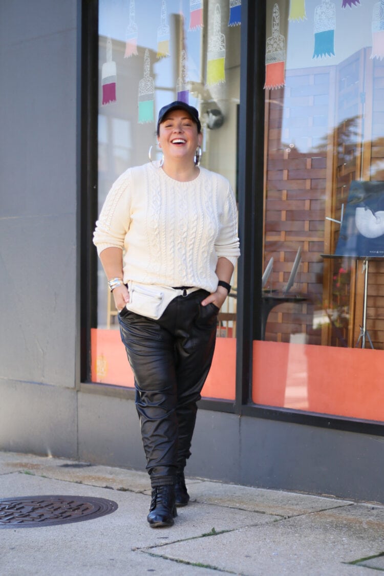 Wardrobe Oxygen styling a cream cableknit sweater with black faux leather joggers and a Brandon Blackwood belt bag