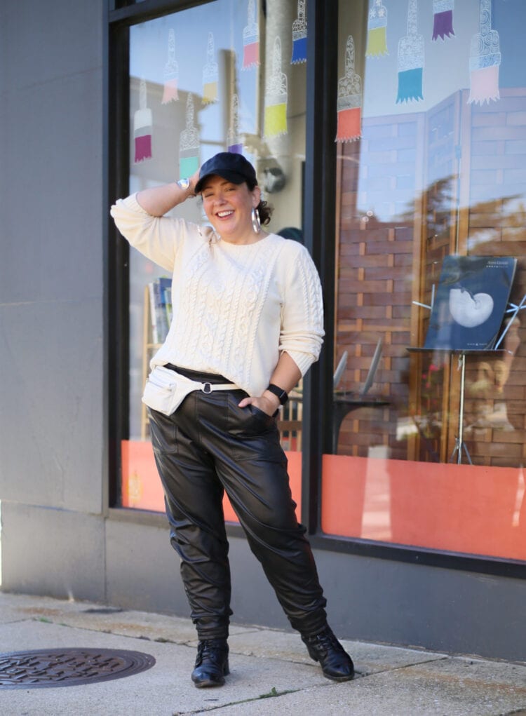 Alison of Wardrobe Oxygen in a cream cableknit sweater and black faux leather joggers.