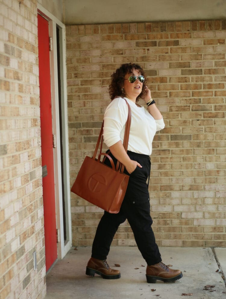 Alison of Wardrobe Oxygen wearing a medium TELFAR bag over her shoulder as she walks out from a brick building