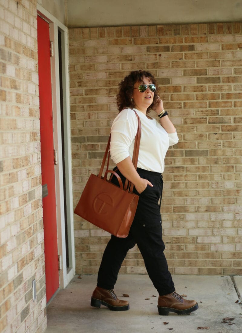 Alison of Wardrobe Oxygen wearing a medium TELFAR bag over her shoulder as she walks out from a brick building