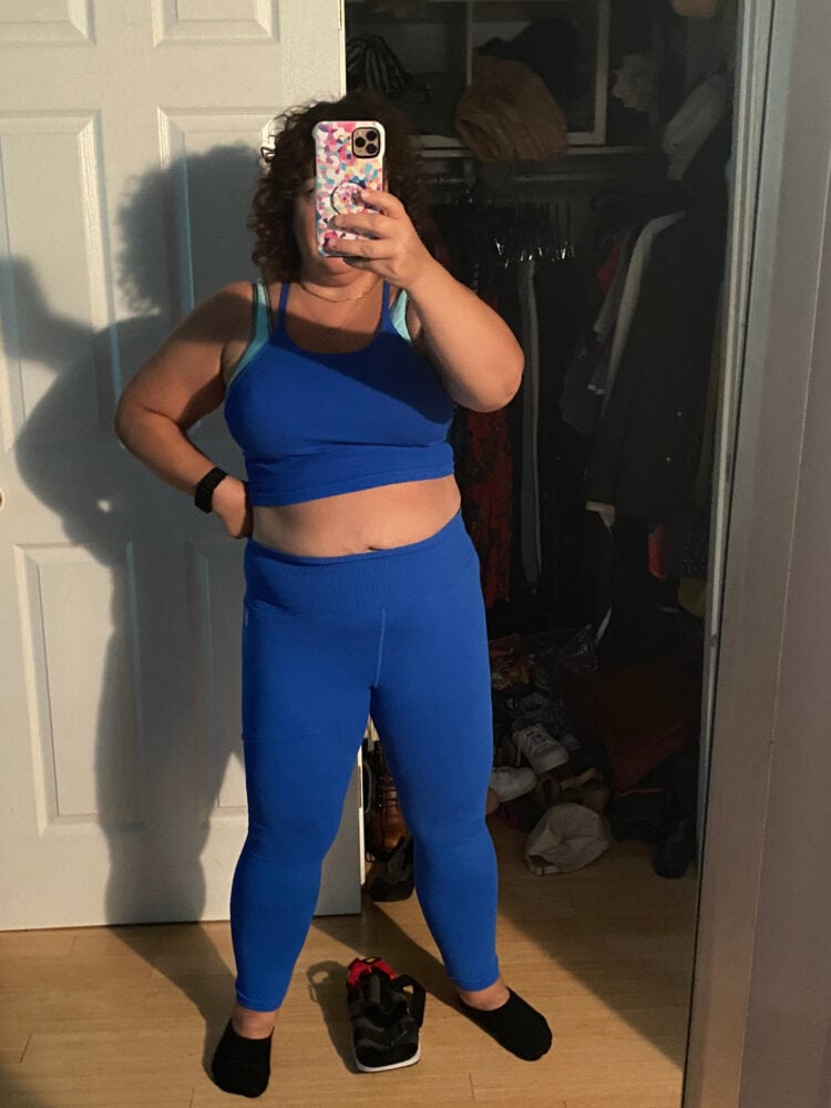 A mirror selfie on a middle aged woman in her bedroom, in ill-fitting activewear from FP movement