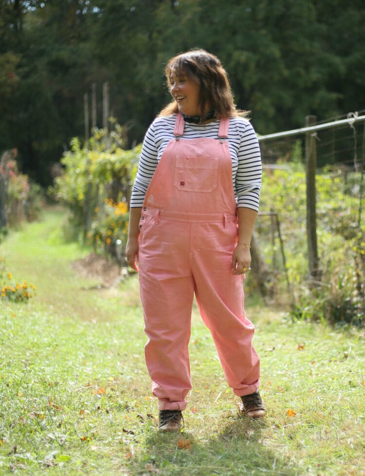 Wardrobe Oxygen in pink Dickies overalls from Grapefruit WV. She is standing in a garden and smiling