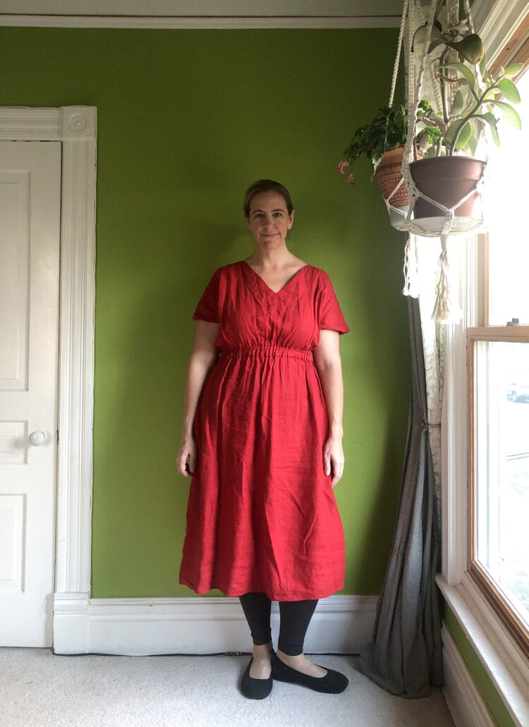 Woman in a red midi length dress from House of Flint, styled over black leggings and black flats