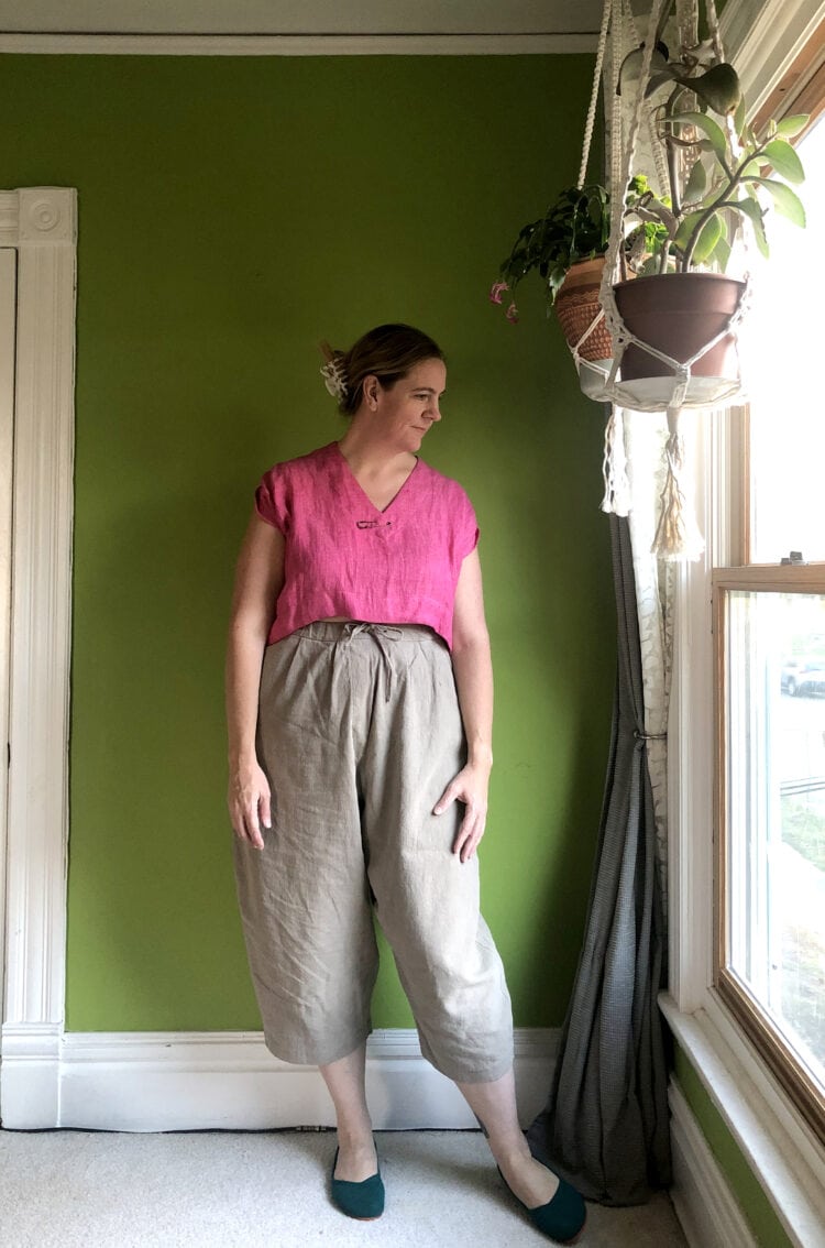 Woman in a pink linen short sleeve top tucked into khaki linen cropped drawstring pants