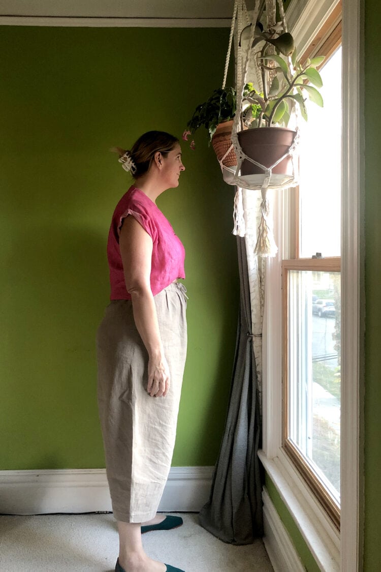 Side view of a woman in a pink top tucked into khaki drawstring cropped pants