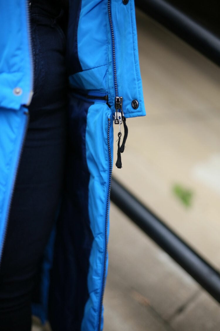 A closeup of the zippers on the Universal Standard 4-in-1 hybrid puffer in electric blue