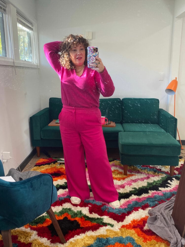 Alison in a pink Universal Standard cashmere v-neck sweater tucked into bright pink wide-leg pants from Banana Republic. She is wearing off-white FILA Electrove 2 sneakers.