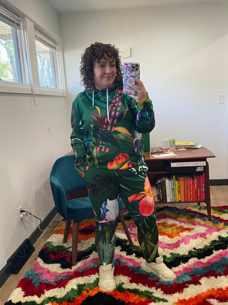 Alison wearing a green floral hooded sweatershirt and matching joggers from the Black woman owned athleisure brand Dressed in Joy