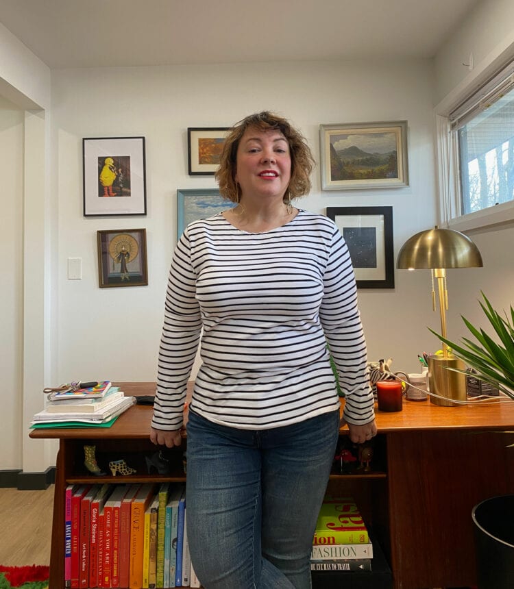 Alison wearing a white with black striped Breton t-shirt untucked with jeans.