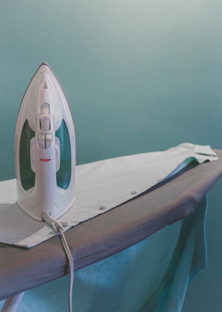 an iron and linen shirt on an ironing board. Ironing linen may soften the fabric and make it more comfortable to wear. For more tips visit wardrobeoxygen.com