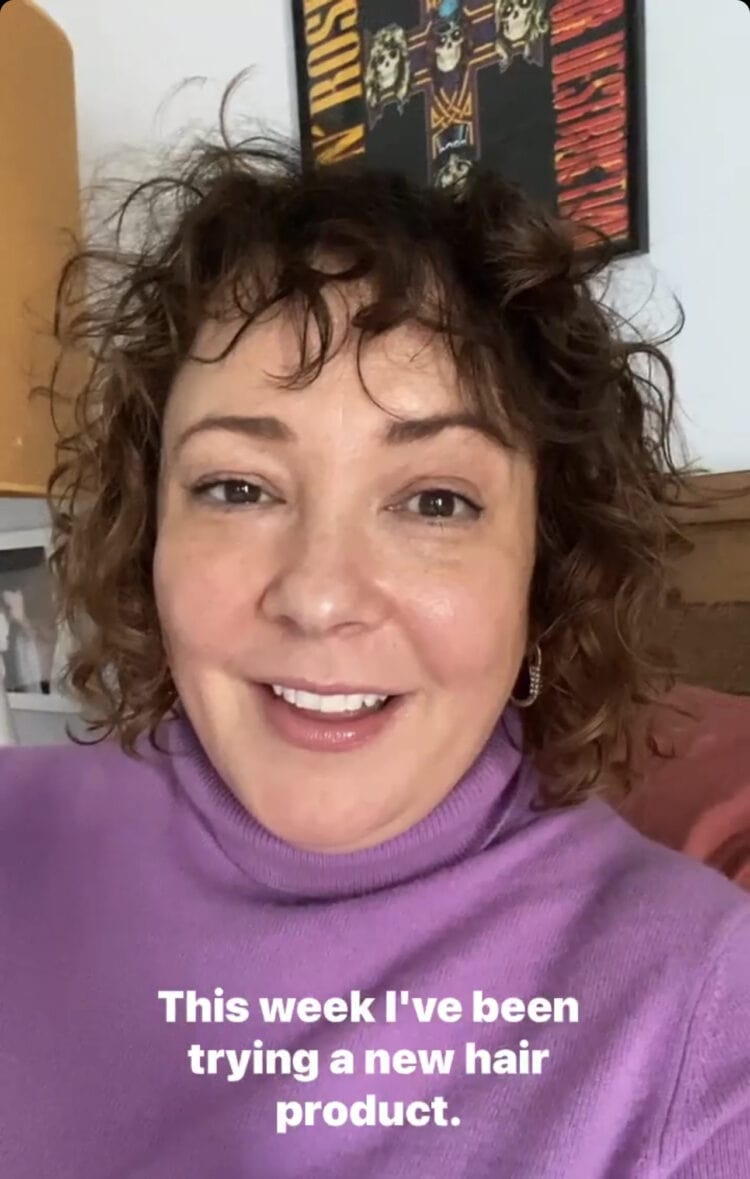 Screenshot from Instagram Stories of Alison with curly shoulder length hair wearing a lavender cashmere turtleneck sweater from Talbots. She is speaking and the caption says, "This week I've been trying a new hair product."