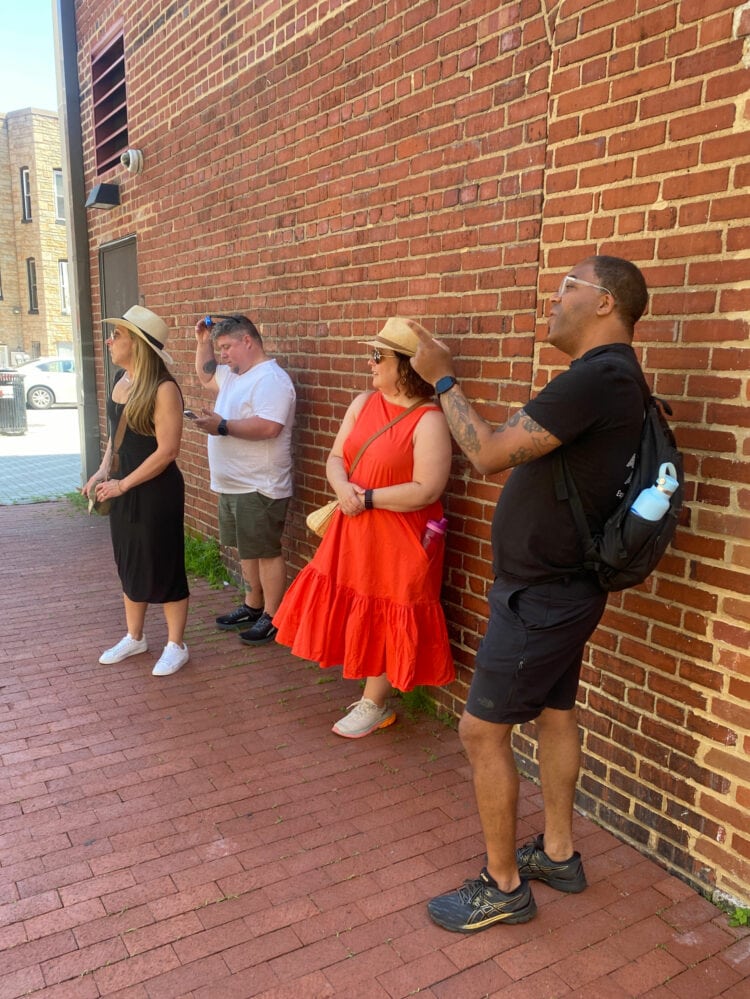 Standing against a brick wall on U Street, Learning more about DC from Tim of Attucks Adams Walking Tours