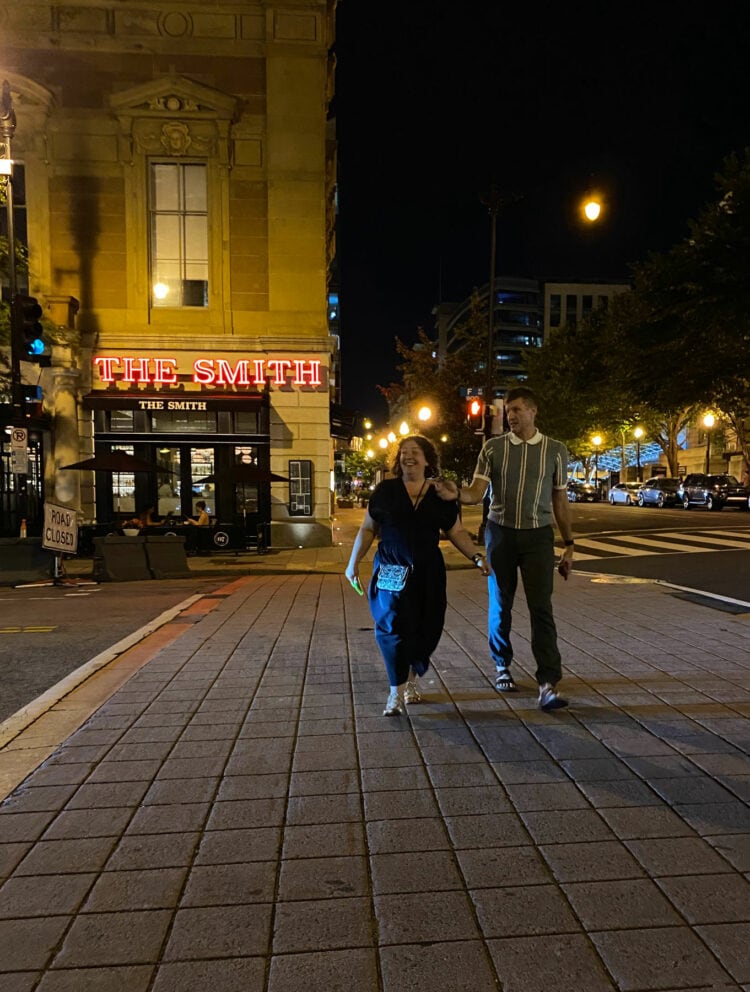 A couple walking across the street in front of The Smith in Washington DC