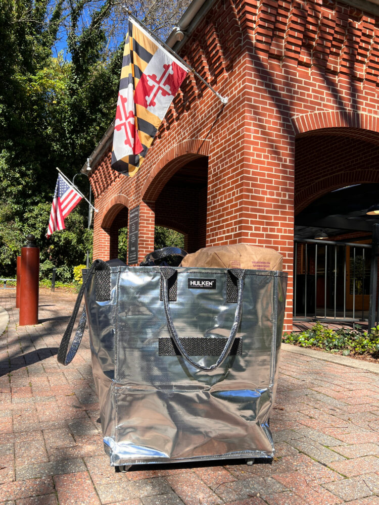 A photo of the large Hulken bag in silver in front of a brick building
