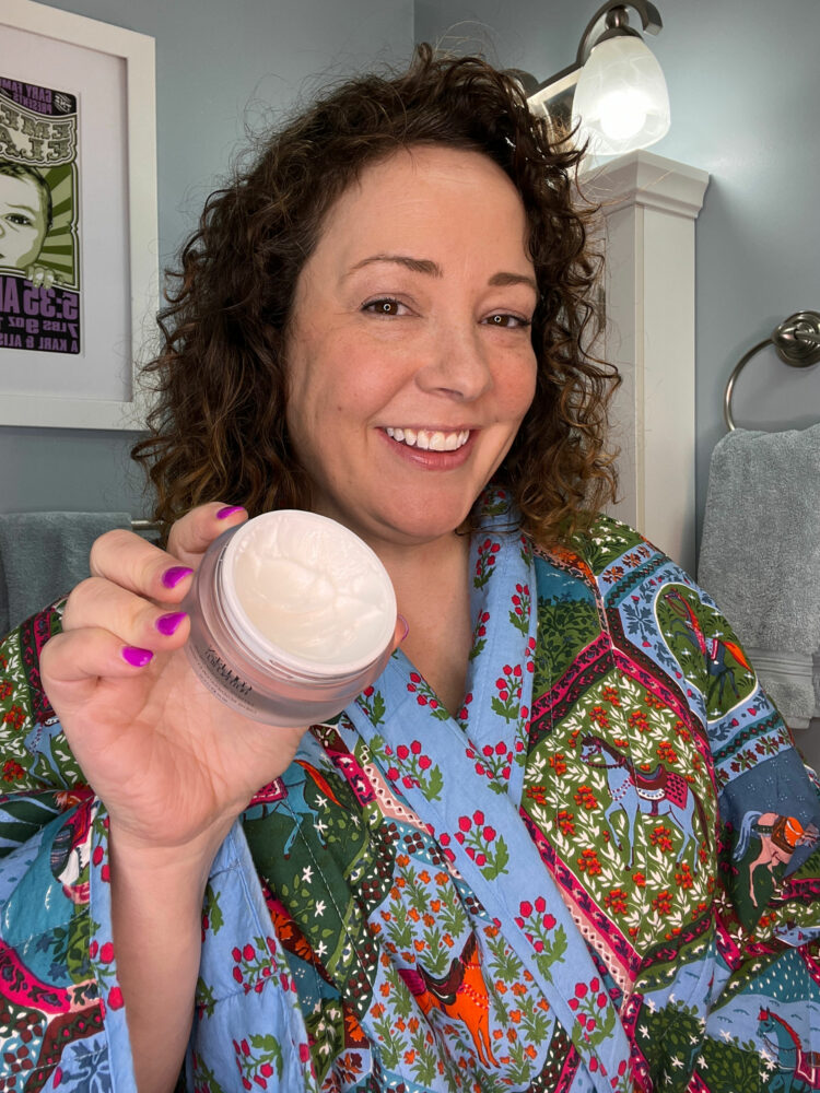 Alison Gary of Wardrobe Oxygen is wearing a quilted Printfresh bathrobe and holding a jar of Colleen Rothschild Extreme Recovery Cream