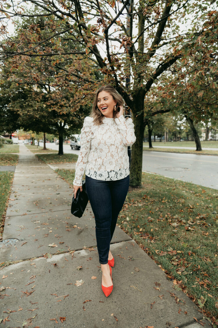 Influencer Caralyn Mirand Koch walking down a sidewalk waring a snakeskin blouse over dark wash skinny jeans. She is wearing bright orange suede pointed toe flats.