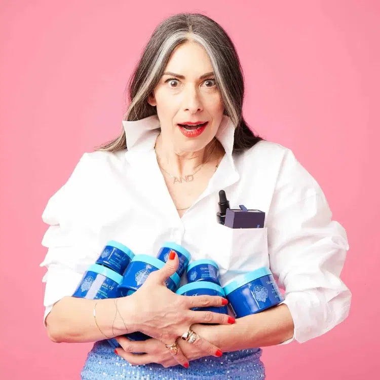 Photo of Stacy LOndon making a shocked face, holding a handful of her now dfunct menopause product brand State Of