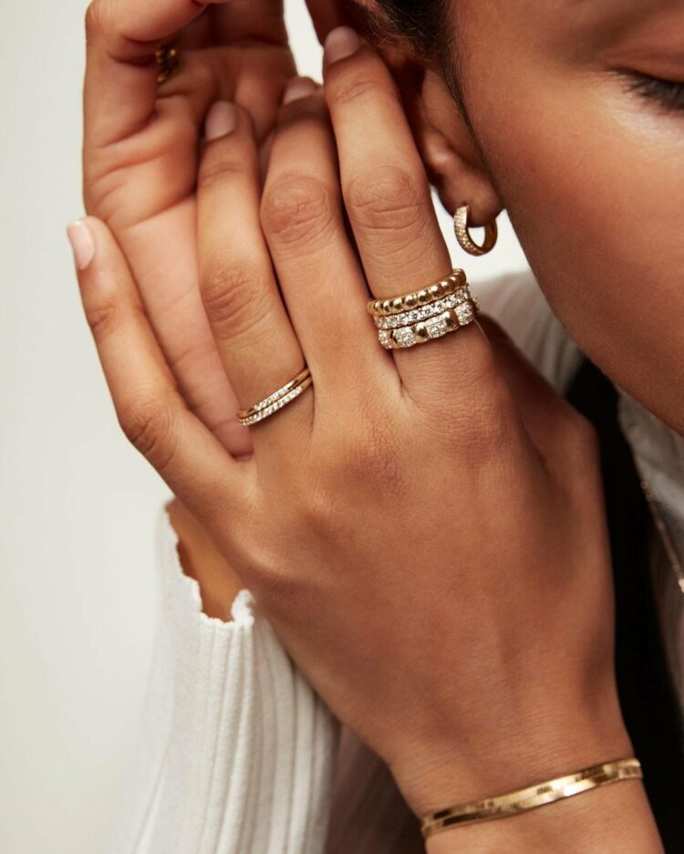 Image of a woman's hand wearing multiple gold rings from Mejuri, a woman-owned jewelry line that offers stylish rings for larger hands.