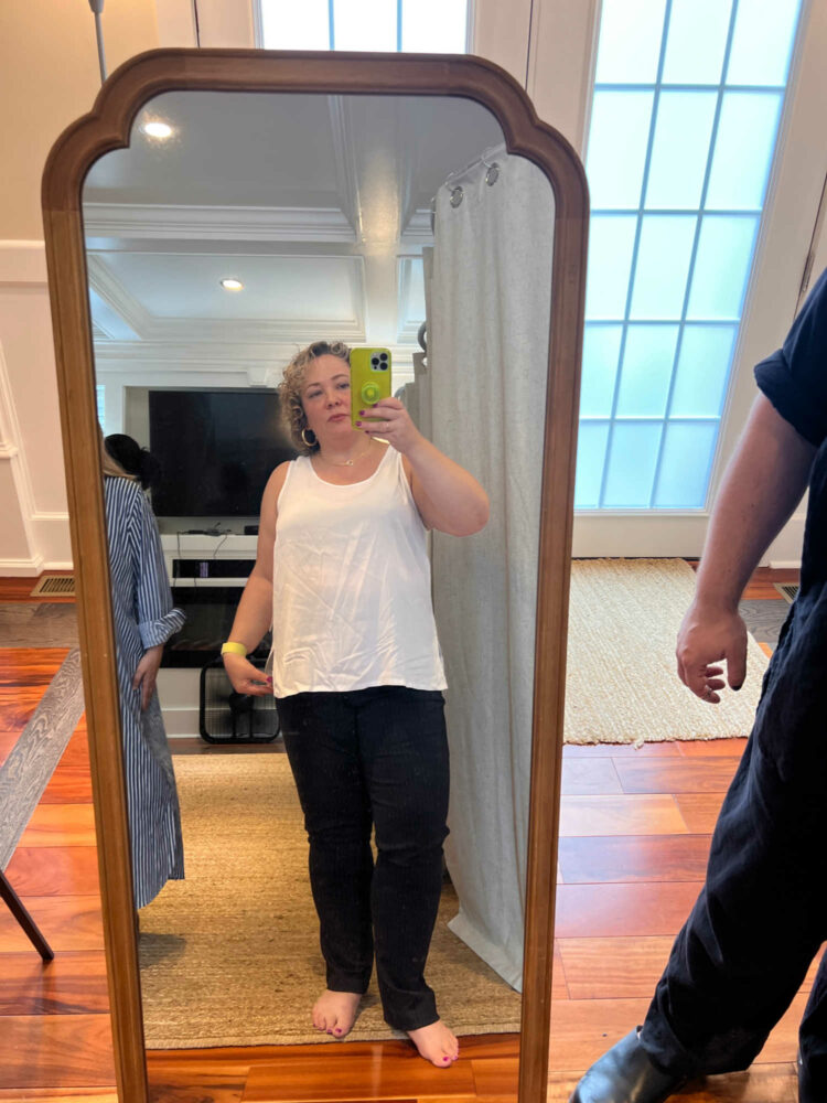 woman trying on a white drapey tank at a Universal Standard trunk show